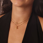 Close-up of a person wearing two gold necklaces with a black background