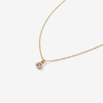 Gold necklace with a heart-shaped pink gemstone pendant on a white background