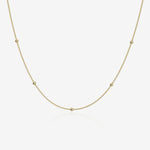 Gold ball chain necklace on a light beige background