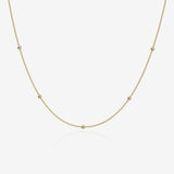 Gold ball chain necklace on a light beige background