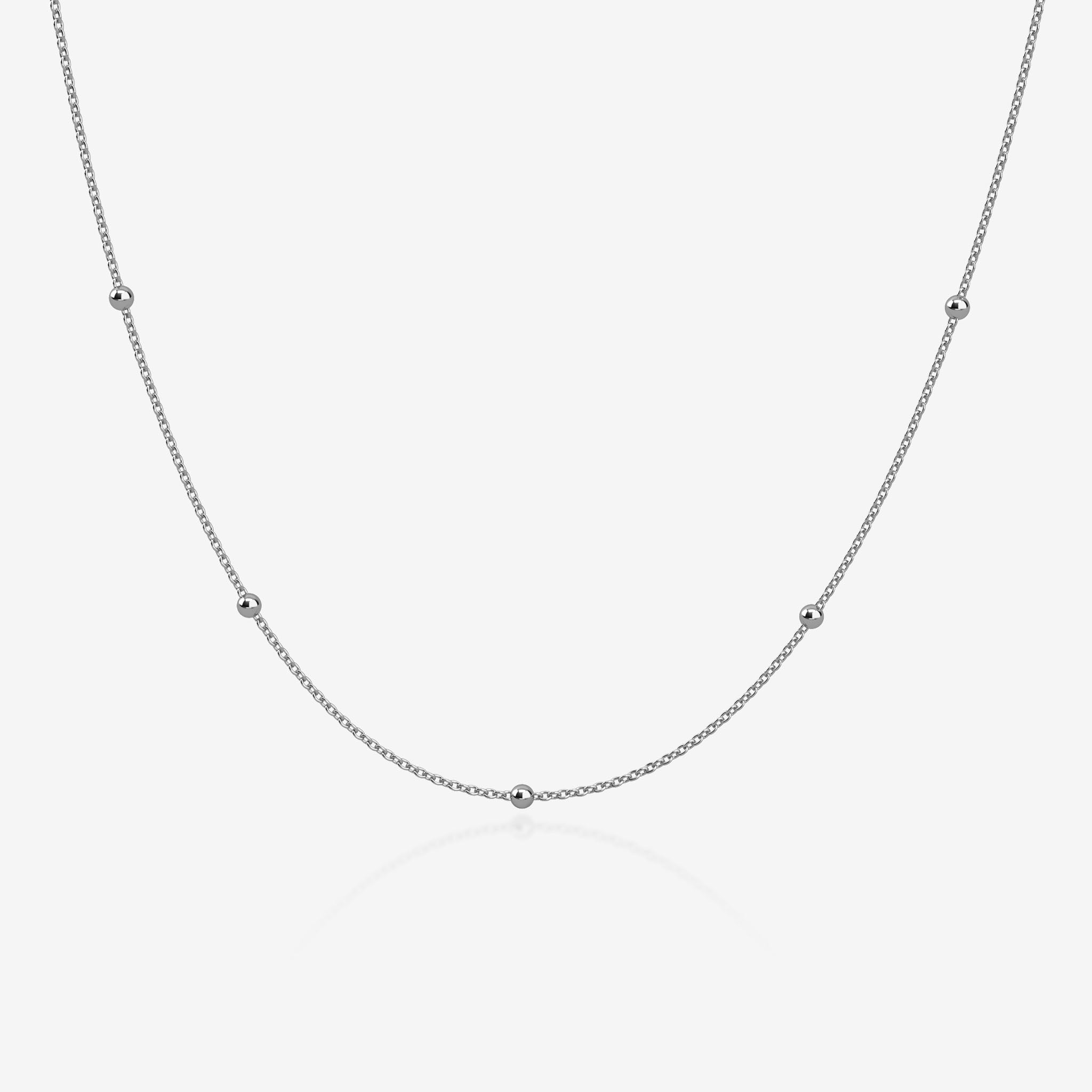 Silver ball chain necklace on a light gray background